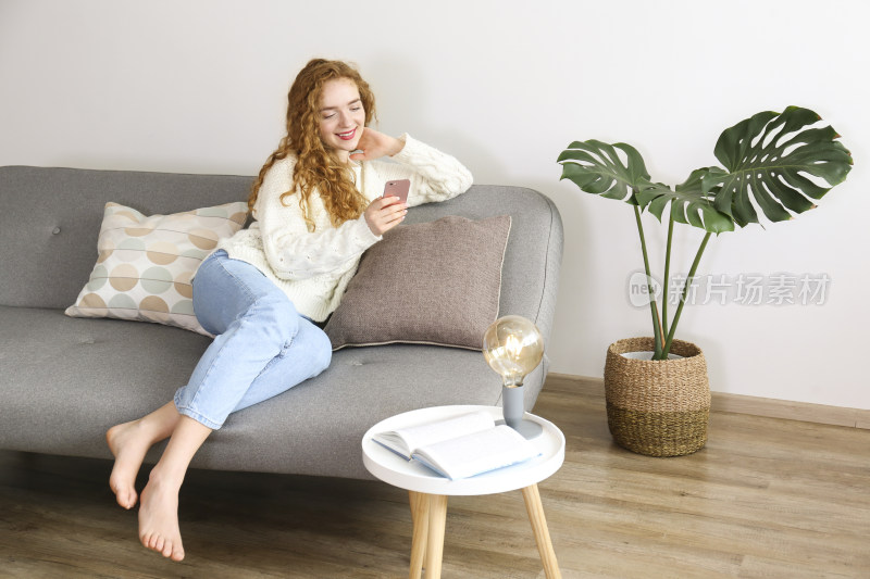 女子居家沙发上玩手机