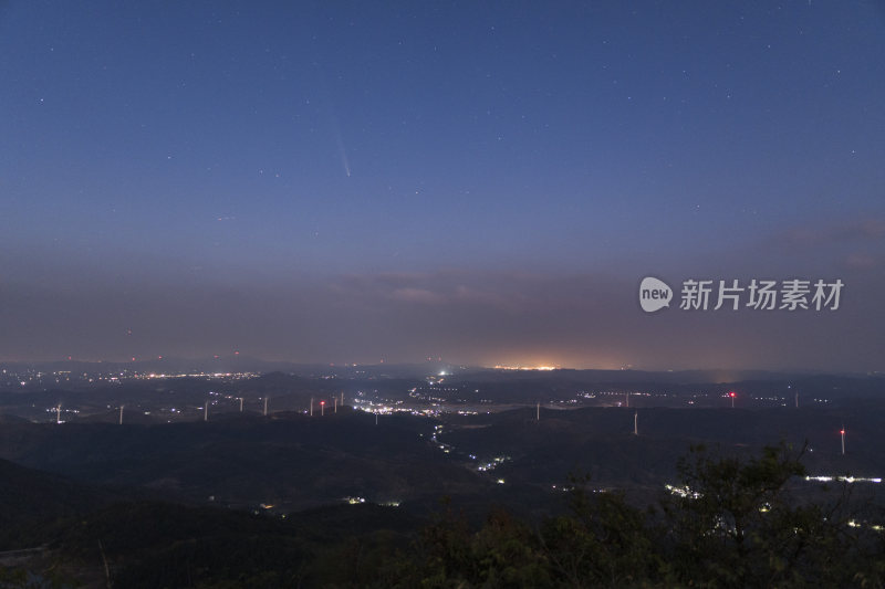 城市上空夜晚彗星落下山间风车群的壮观景象