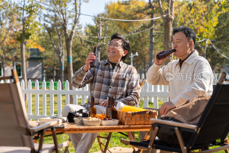 两个老年男人坐在露营地喝啤酒