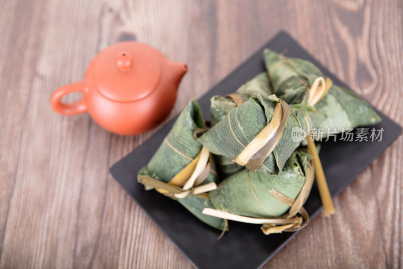 桌子上一盘端午节的粽子和一壶茶