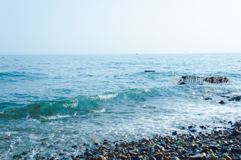 海浪轻抚冲刷岸边鹅卵石海滩