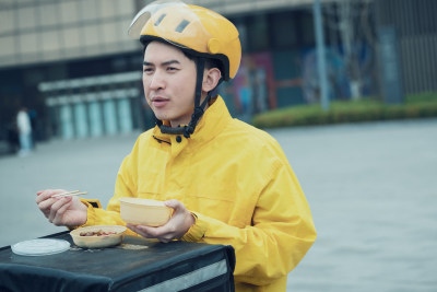 在户外吃饭的青年外卖员