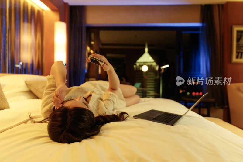 年轻女人躺在床上看手机