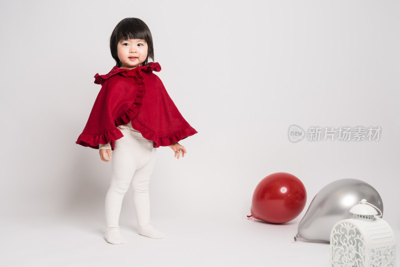 白色背景前穿红色披风的中国女童