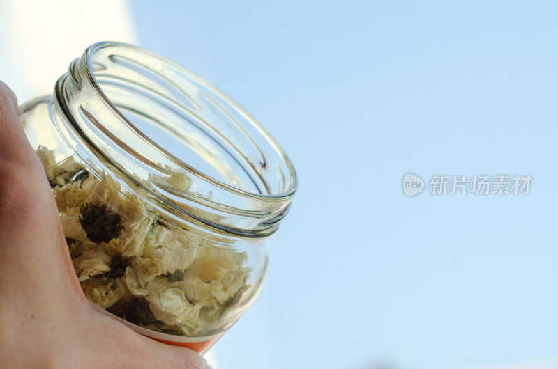 蓝天下手拿一瓶白菊花茶