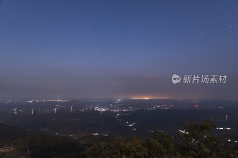 城市上空夜晚彗星落下山间风车群的壮观景象