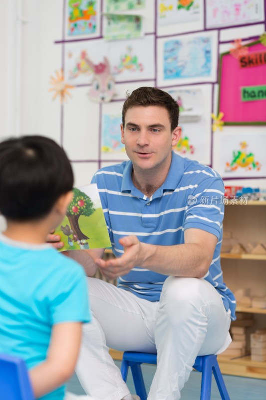 幼儿园外教男老师和儿童一起看画册