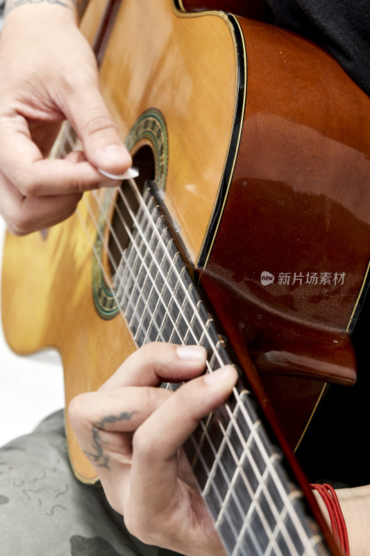 示范演奏古典吉他的亚洲男性乐手人像局部特写