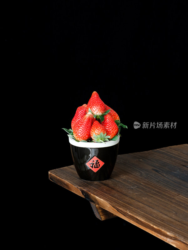黑色背景上，一篮子的新鲜水果草莓