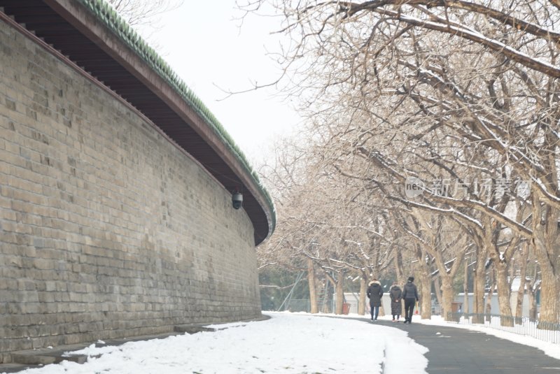 古城墙旁雪中小路行人漫步