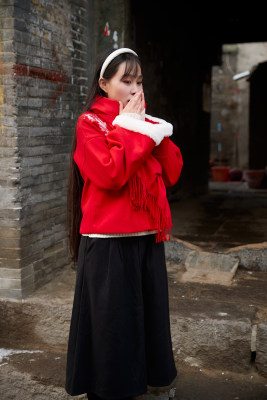 雪后在老城古巷穿着喜庆服饰的亚洲少女