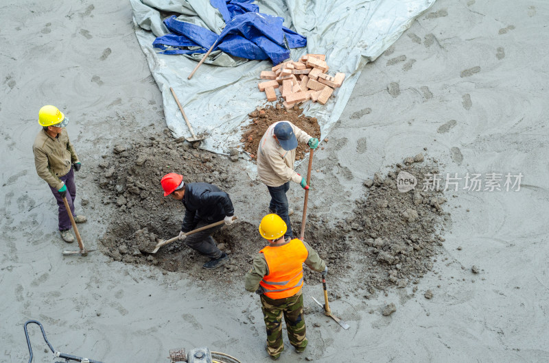 建筑工地上几个合作挖坑的建筑工人