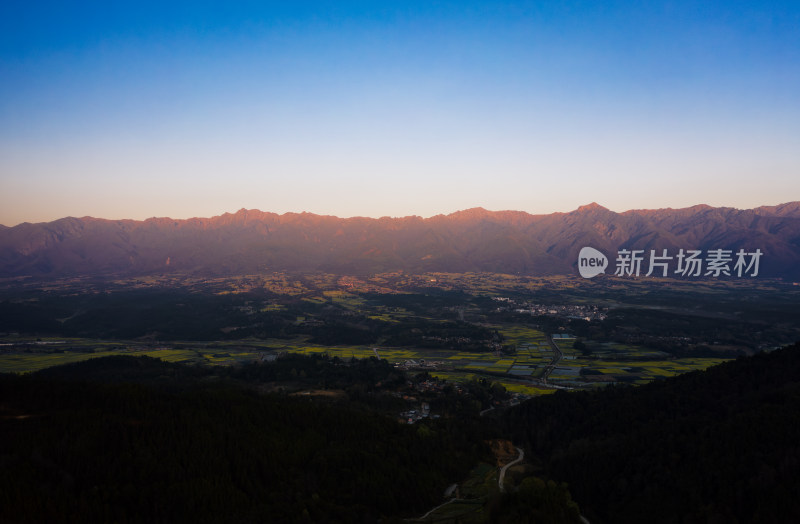 日出时分的壮丽山脉与山脚下的田野风光