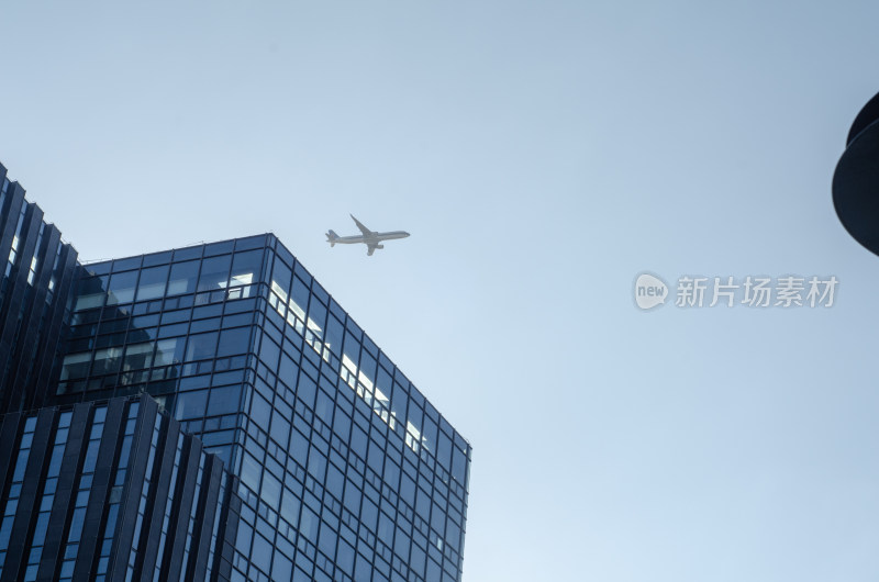 仰拍天空中飞过高楼的飞机