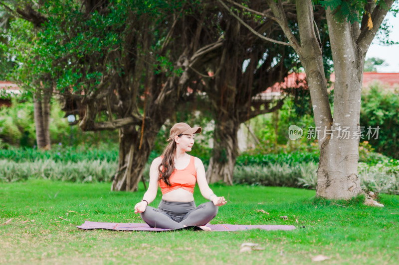 在户外绿色的草地上做瑜伽的亚洲女性