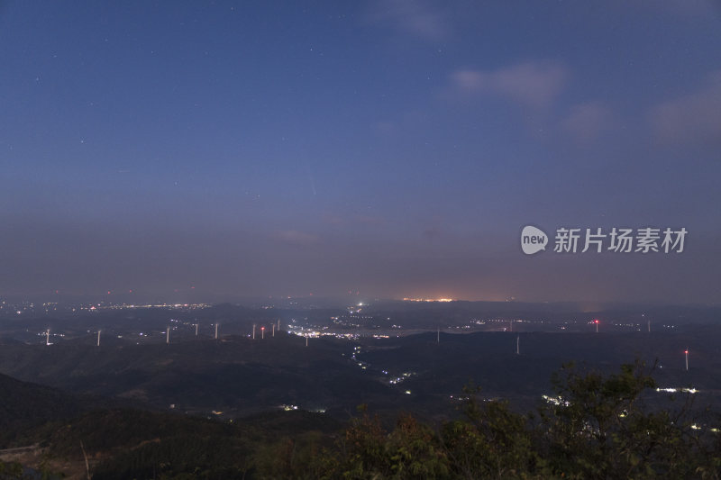 城市上空夜晚彗星落下山间风车群的壮观景象