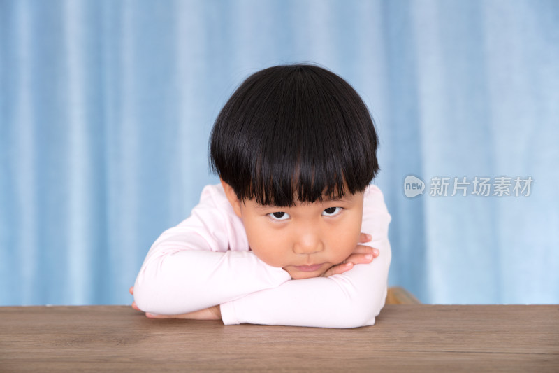 趴在桌子上抬眼看镜头的中国小姑娘