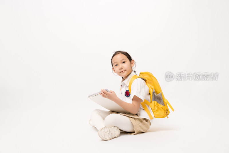 坐在白色背景前在作业本书上写的中国女孩
