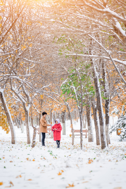 走在公园雪地里的中国母女形象