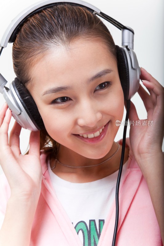 快乐的年轻女人戴耳机听音乐