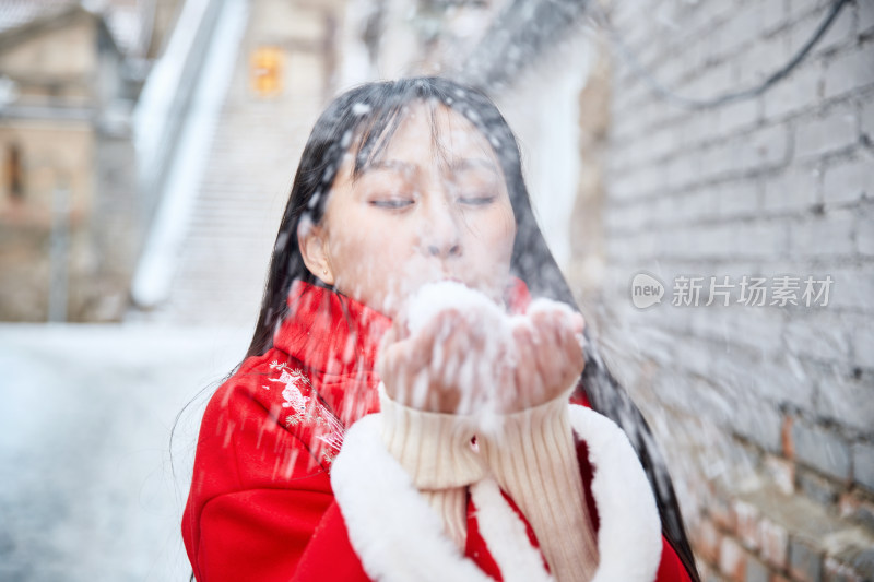 雪后在老城古巷穿着喜庆服饰的亚洲少女