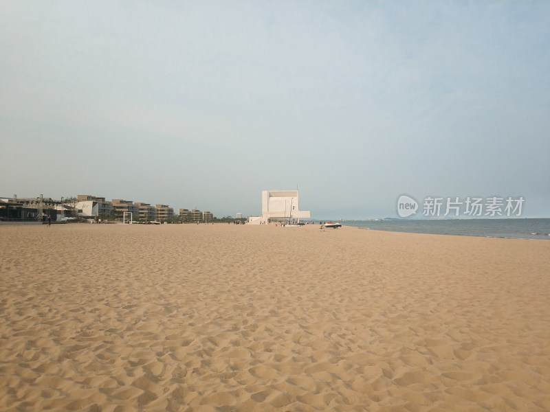 空旷沙滩边有建筑的开阔海边景象