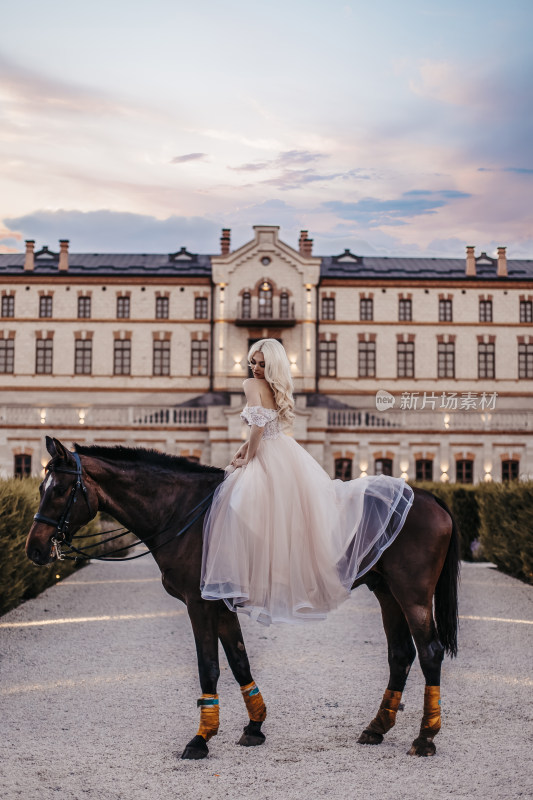 金发女子穿纱裙骑马于古堡前