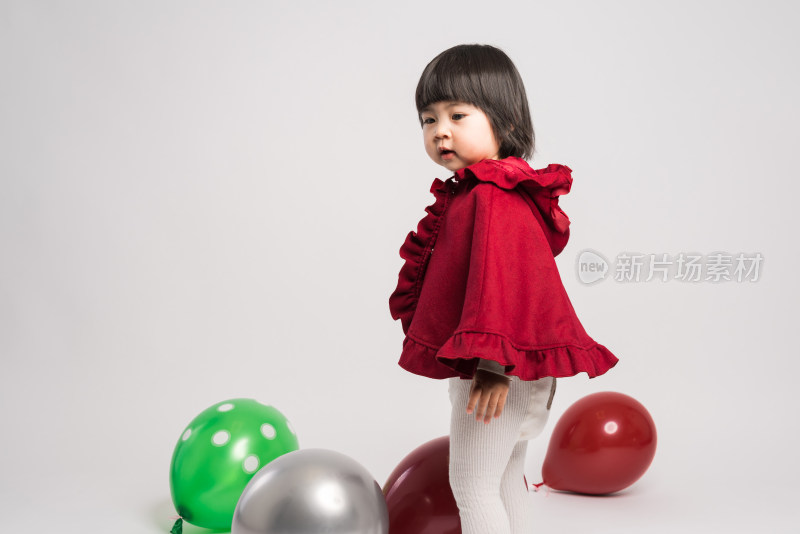 白色背景前穿红色披风的中国女童
