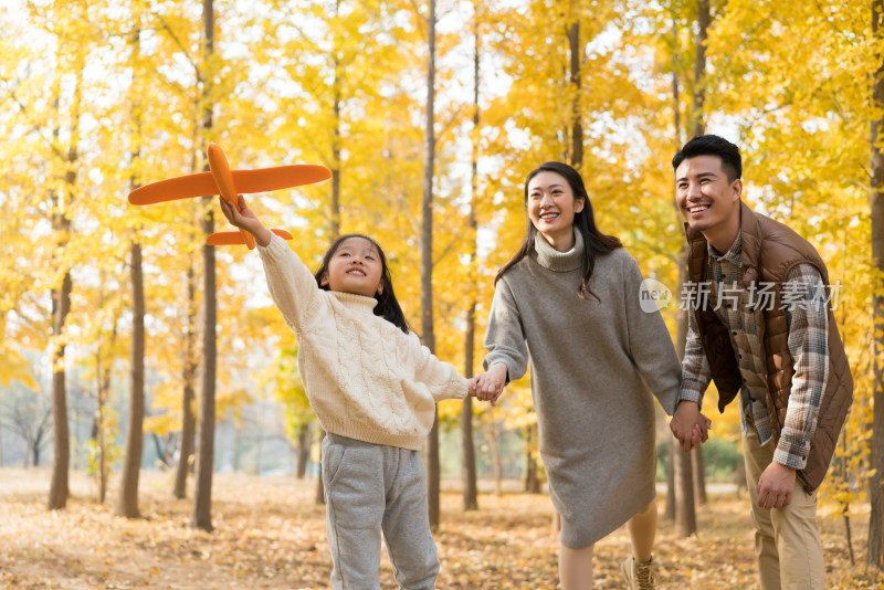 快乐的一家三人秋游漫步银杏林