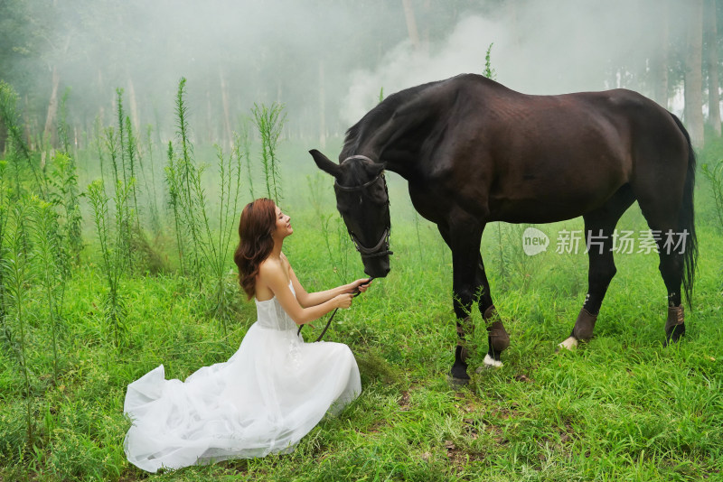 草地上穿婚纱的青年女人牵着马