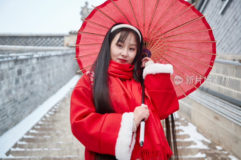 雪后在老城古巷穿着喜庆服饰的亚洲少女