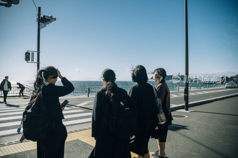 女生在镰仓海边街道结伴同行