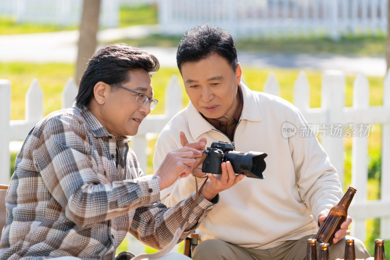 两个老年男人坐在露营地看数码相机