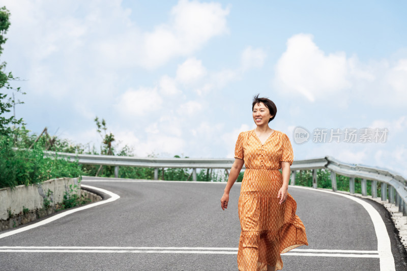 晴朗的夏天午后走在盘山公路上的中国女性