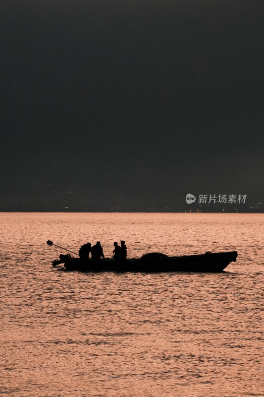 夕阳下海上小船及人物剪影