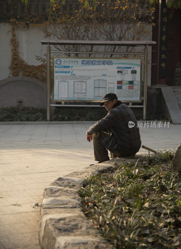 男子坐在校园公告栏前休息