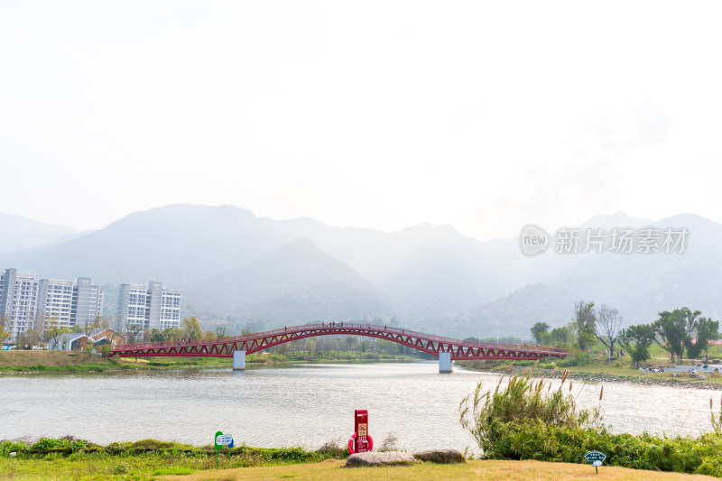 河畔红色拱桥与远山城市景观