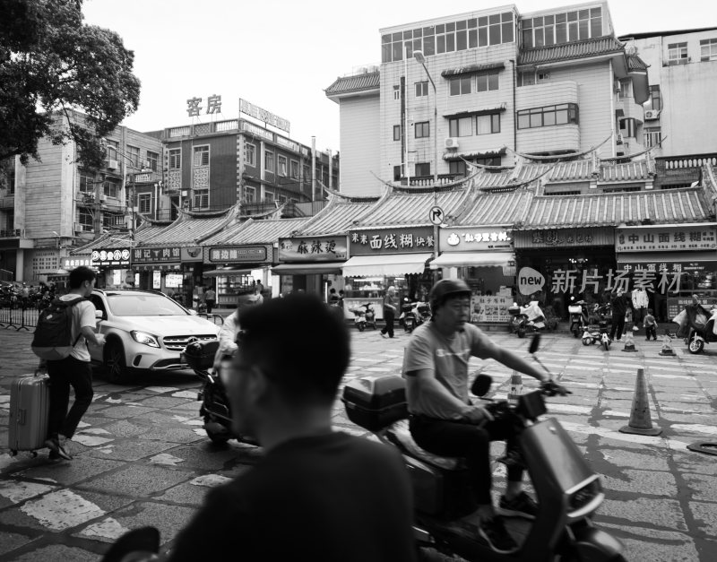 骑摩托车男子行驶在市井街道的场景