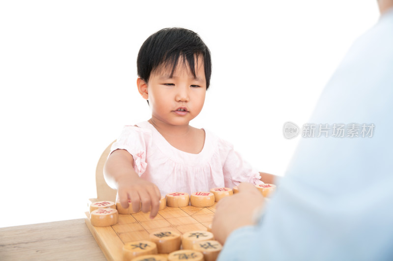 黄皮肤小女孩在认真的和大人下中国象棋