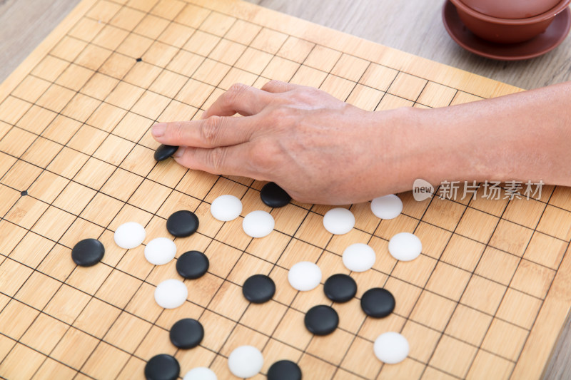 俯视拍摄手拿围棋棋子在棋盘上落子