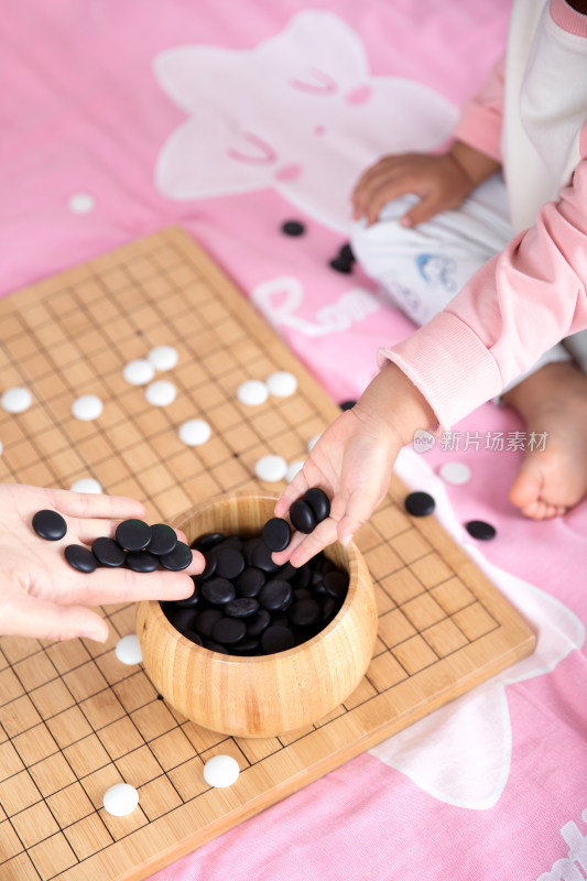 一只小手正把棋子放入棋盒中