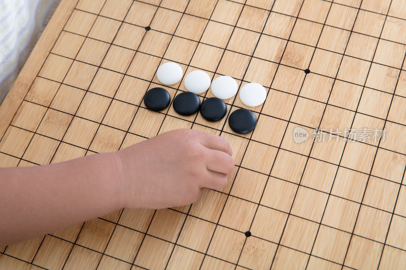 小手拿着棋子在围棋棋盘上下棋