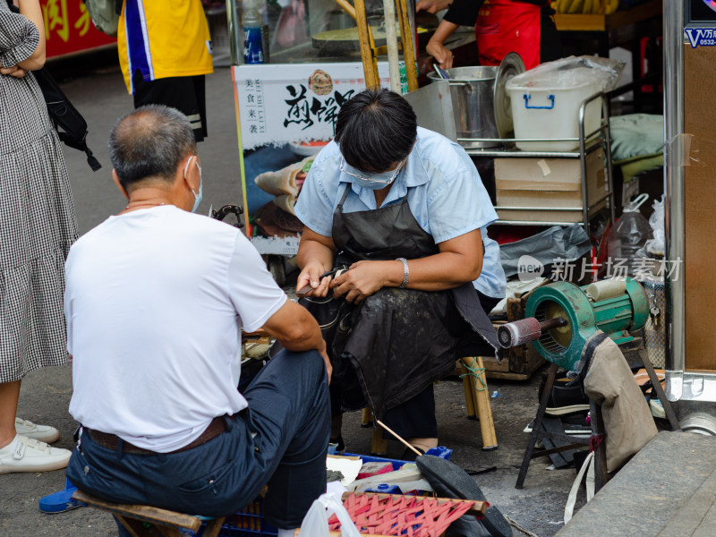 街头上正在修鞋的老修鞋匠和一位顾客