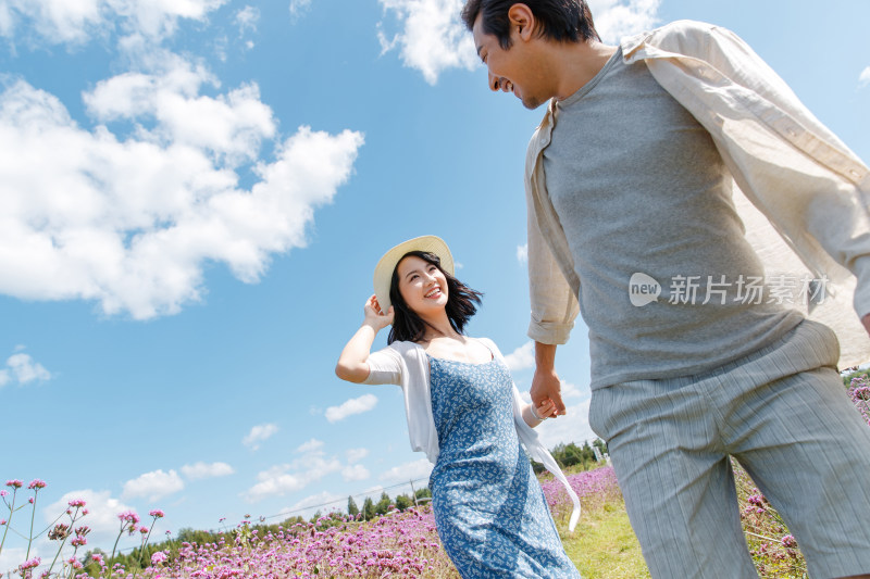 青年夫妇手牵手在花海里奔跑