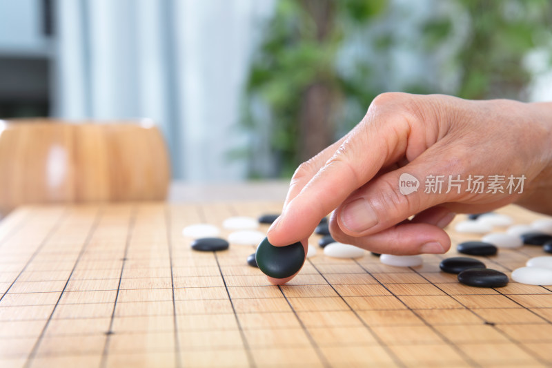 一只手夹着一枚黑色围棋棋子预要落下