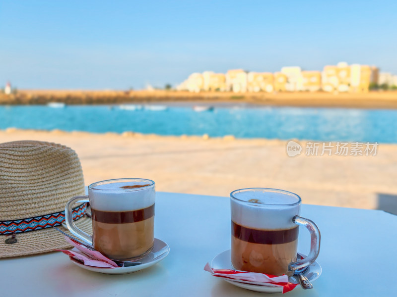 海滩边桌上的两杯咖啡与草帽