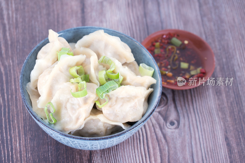 俯视一碗煮熟的饺子和一盘蘸料