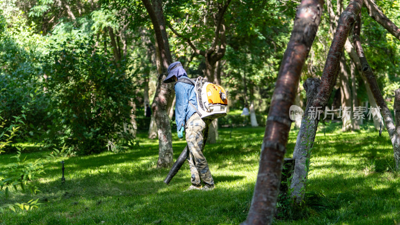 公园里的绿化工人正使用吹草机吹草地