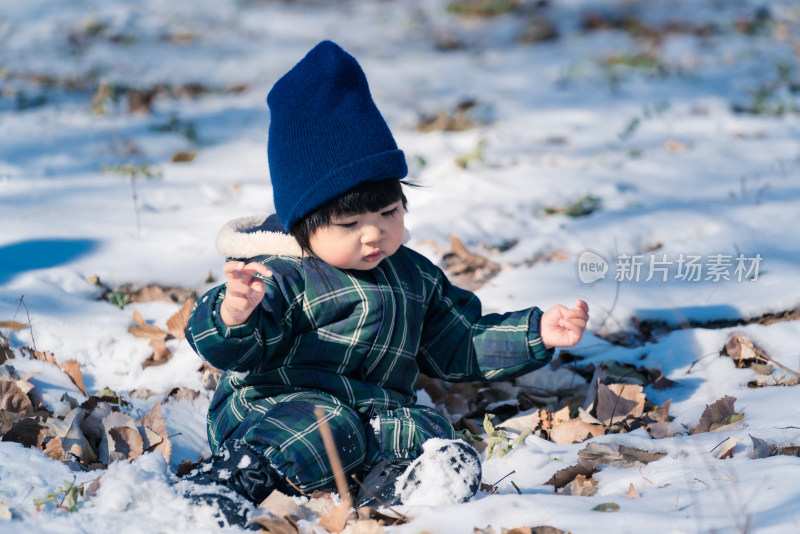 中国北京坐在公园雪地里的女童