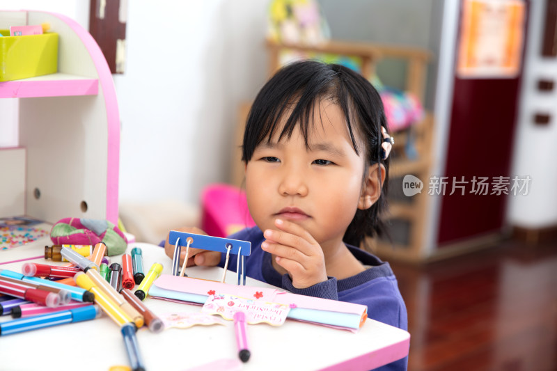 四岁东方小女孩趴在学习桌上玩耍